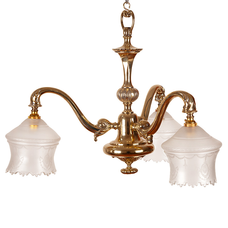 Decorative Edwardian cast brass ceiling pendant light issuing three scrolling branches supporting frosted glass shades decorated with stylised leafy tied swags and medallions (c.1900).