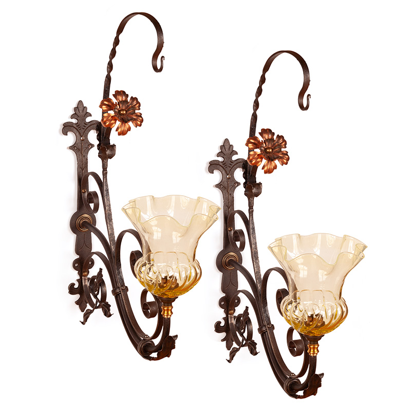 Pair of decorative wrought iron wall lights fitted with copper rosettes supporting green fluted Vaseline shades (c.1900).